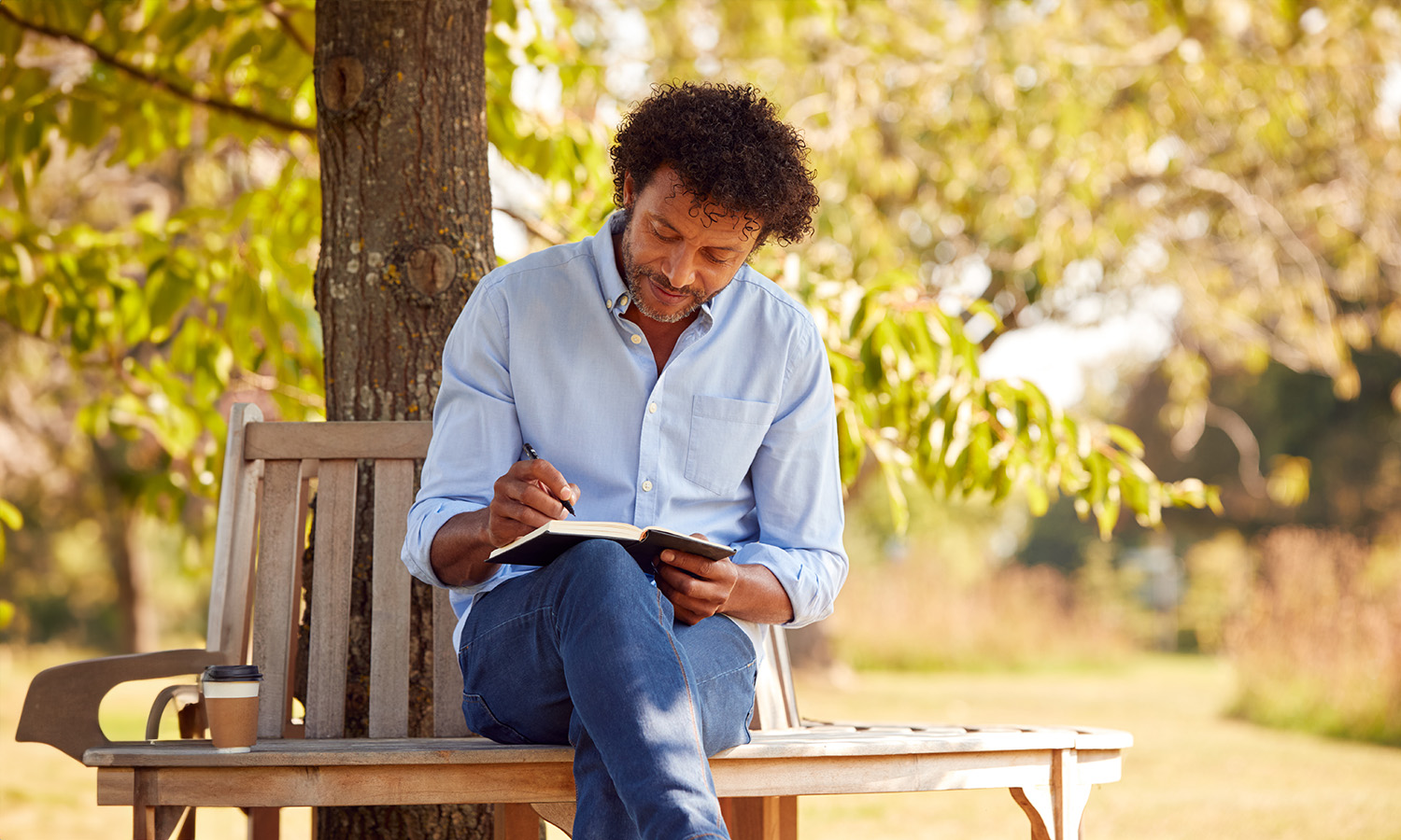 Man writing in a journal in the park. Compassionate Inquiry therapy in North Carolina