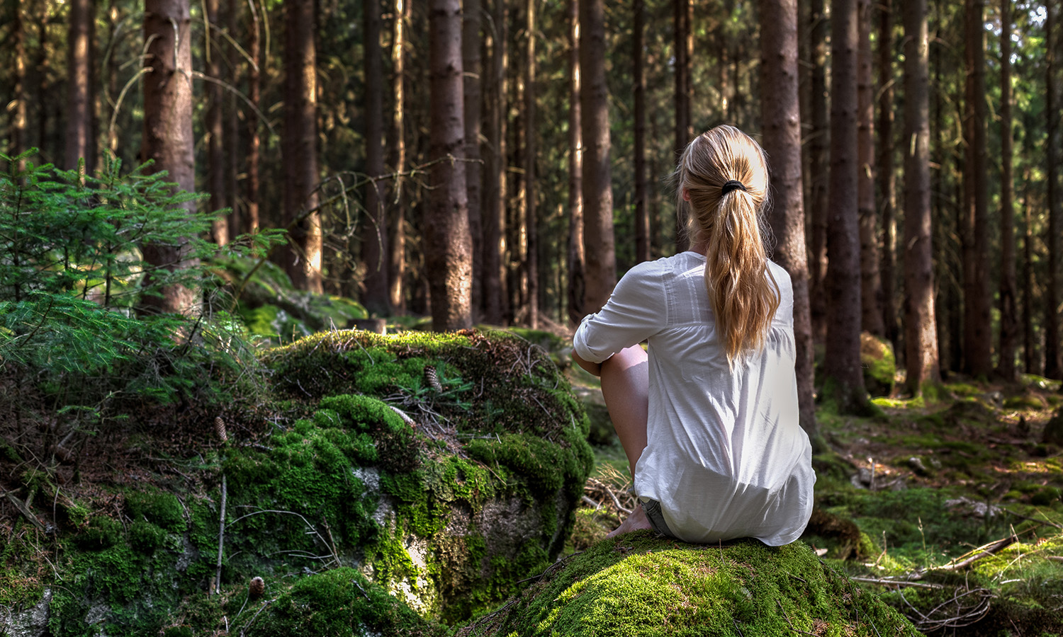 Young woman sitting in the woods contemplating loss. Grief and loss counseling in Raleigh, NC