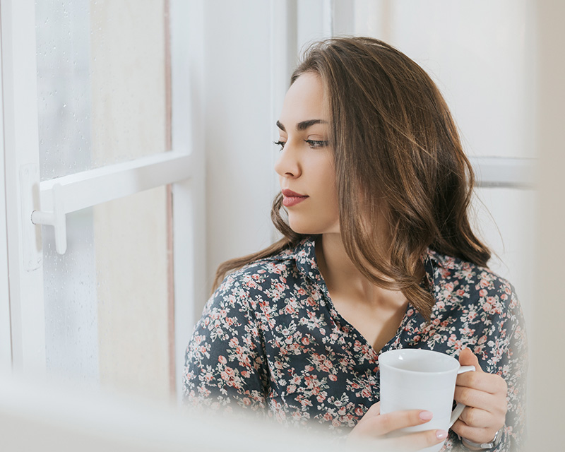 Young woman holding cup of tea needing support through grief