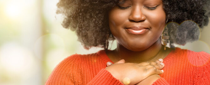 Black woman with hands on hear exploring spirituality in Raleigh, NC