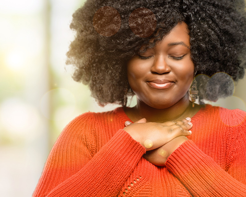 Black woman with hands on hear exploring spirituality in Raleigh, NC